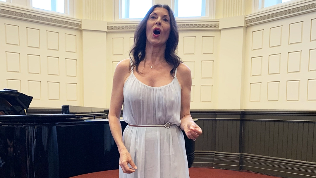 Woman performing in a white dress by a piano.