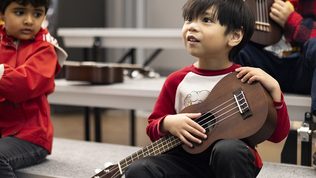 Intro to Instruments student holding an ukulele