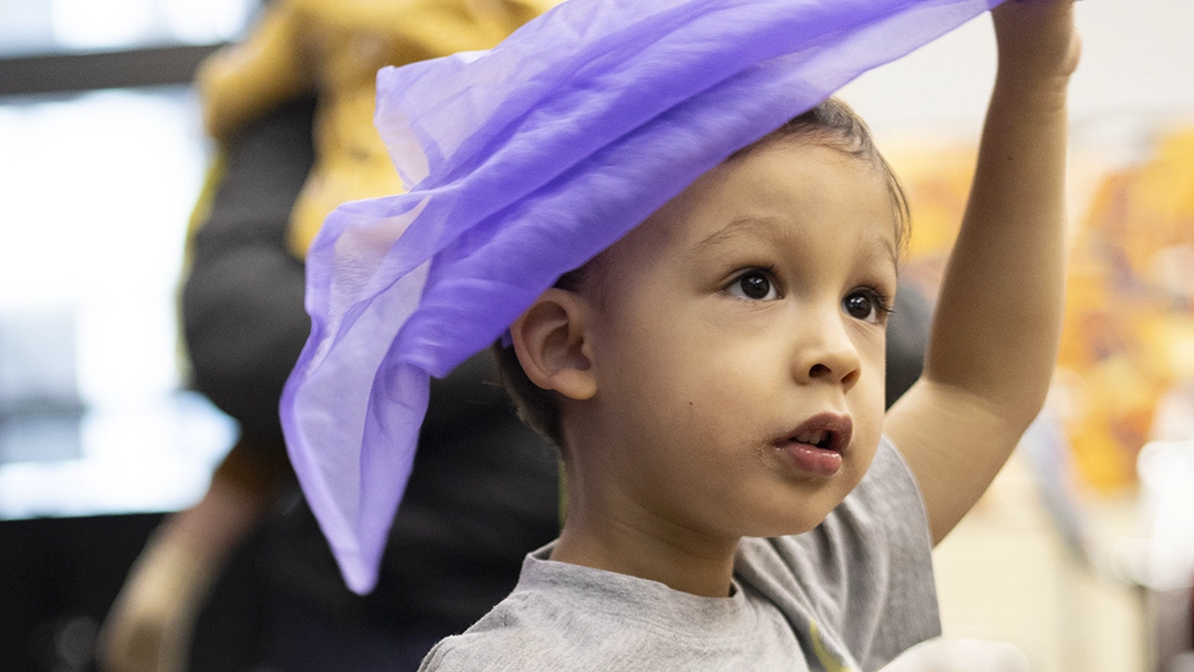 Musical Storytime student holding a play scarf