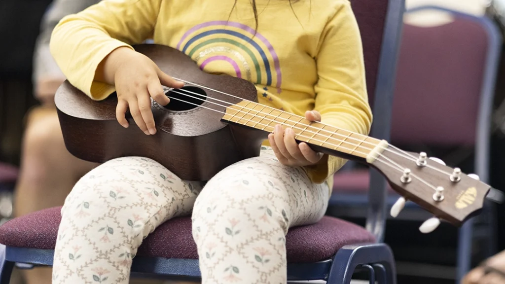 Intro to Instruments student holding an ukulele.