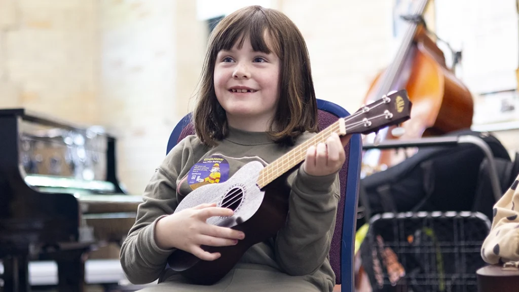 Intro to Instruments student holding an ukulele.