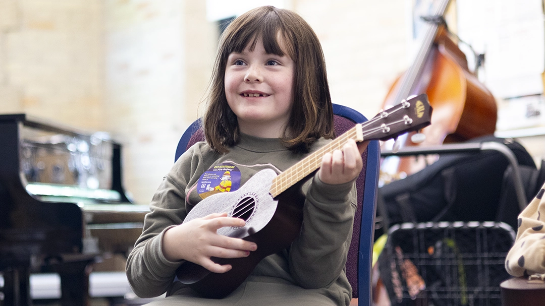 IMG_4831_website Intro to Instruments student holding an ukulele.